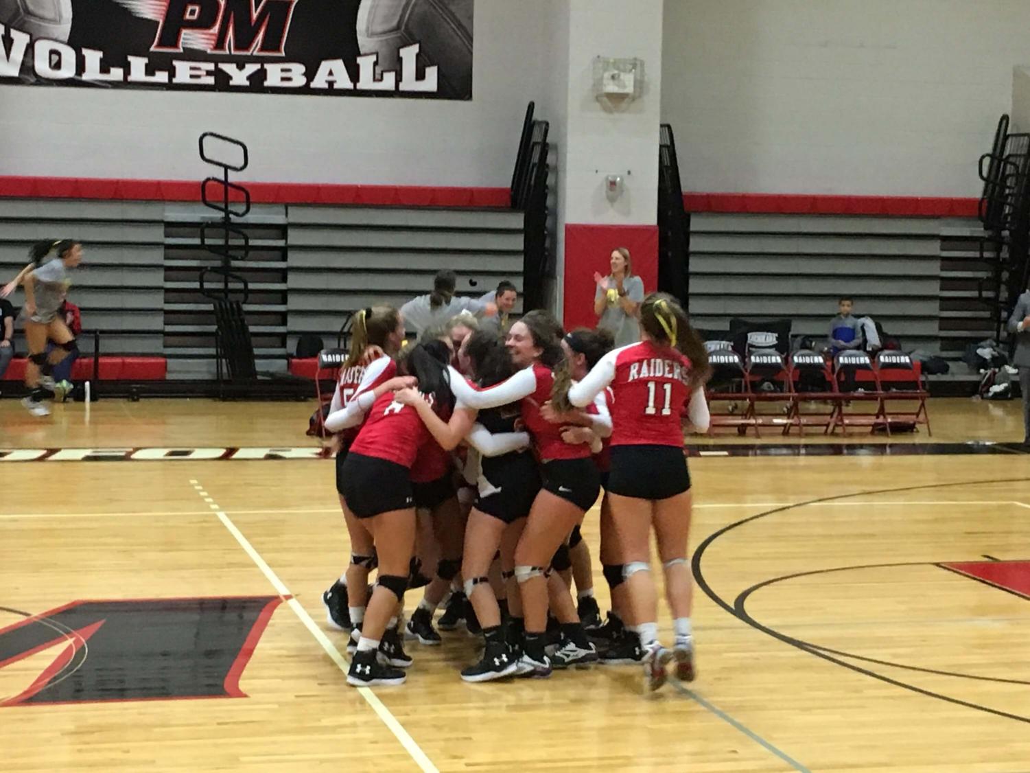 The girls' volleyball team huddle together and celebrate an amazing win over Ward Melville.
