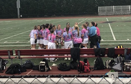 The girls huddle on the field in their Stick it to Cancer Awareness t-shirts and play for a cause Monday night at Raider Stadium.