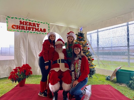Juniors Rachel Stein, Mary Savi, and Nicolette Savattere pose with Santa before getting ready to help direct the runners.
