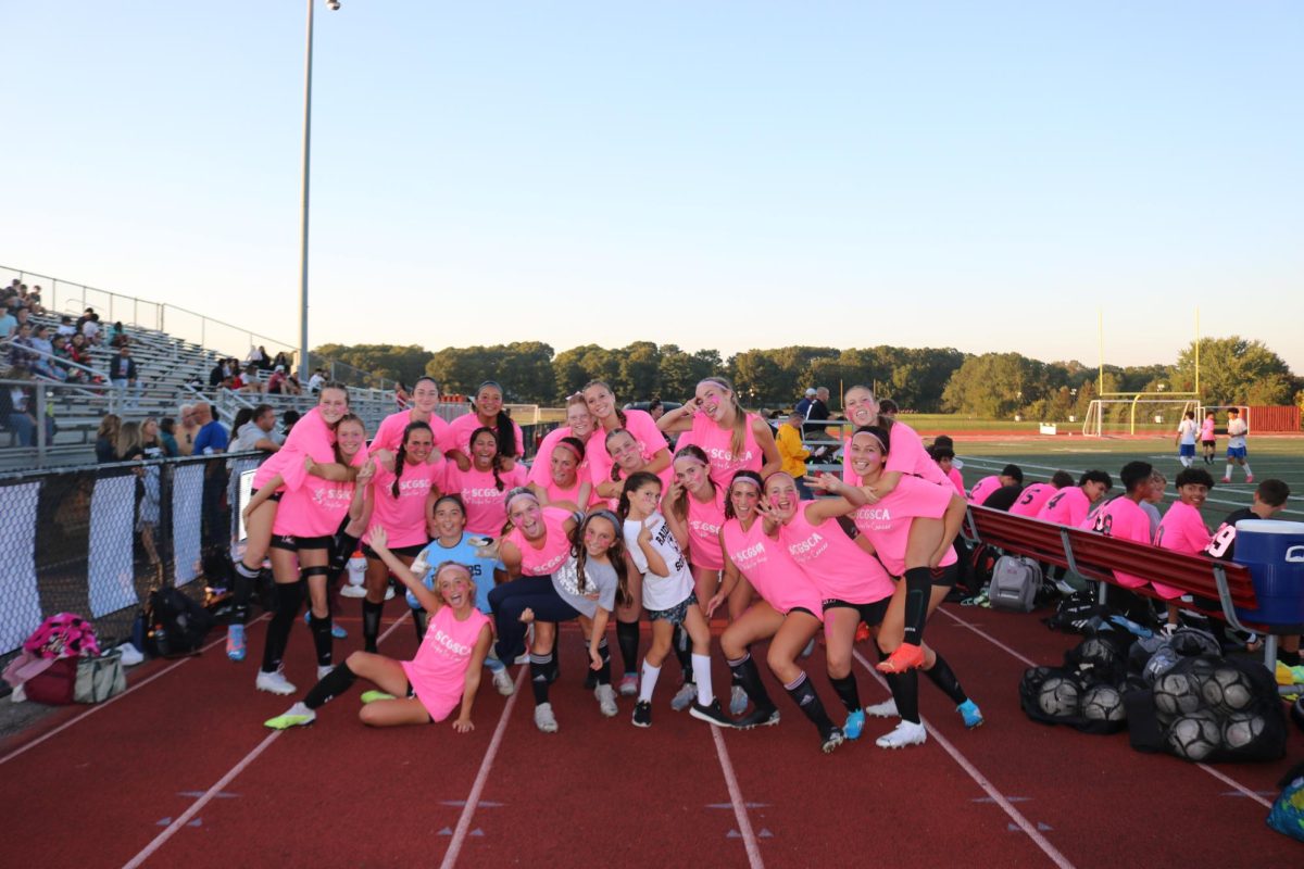 The Girls Varsity Soccer Team strikes a silly pose before their annual Kicks for Cancer game, where they wear pink jerseys in support of breast cancer awareness.