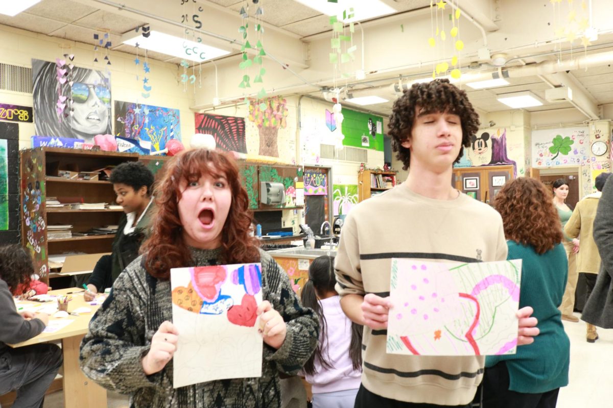 National Art Honor Society members Alex and Ella display examples of the overlapping pattern designs the visiting elementary school students created.