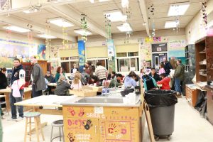 Students, parents, and teachers working together on Valentine's Day themed artworks.