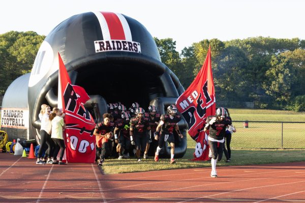 The boys Varsity football team running out of the tunnel and onto the field at Raider Stadium for the very first time.